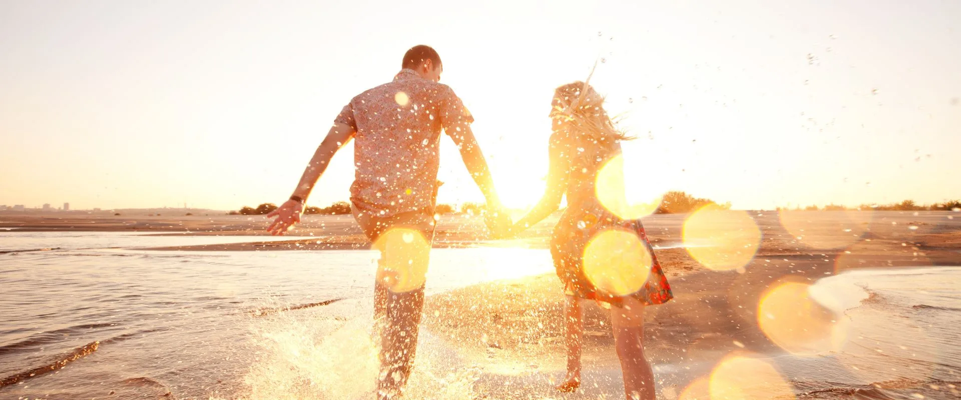 couple races in the water on the beach debating veneers vs invisalign