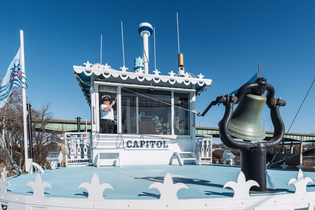 The Captain ringing the bell on a white steamer riverboat.
